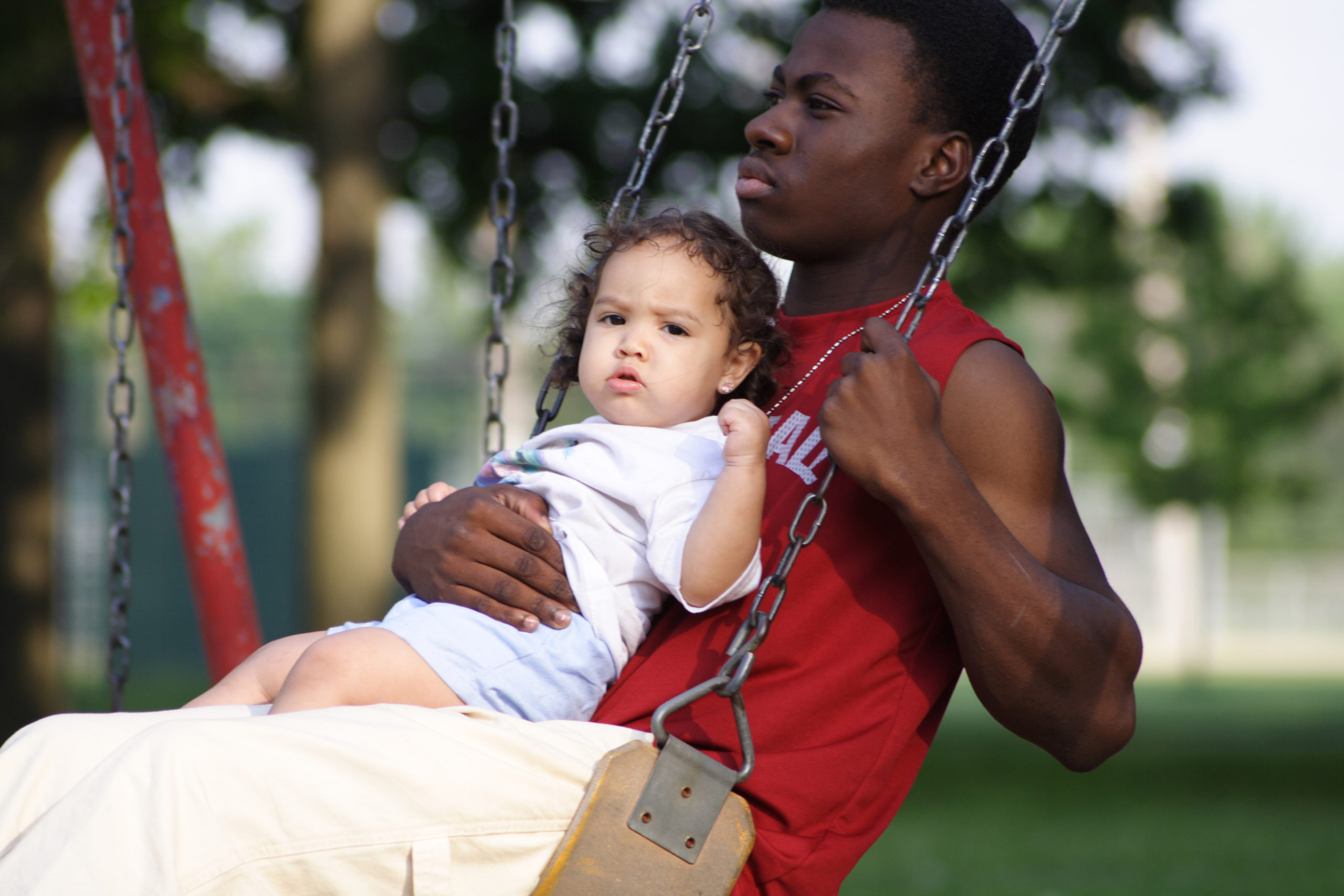 Angry teenage boy swinging with a baby