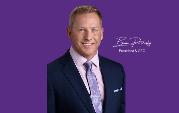 A professional headshot of a smiling man in a blue suit and tie, with a purple background. text overlay identifies him as 