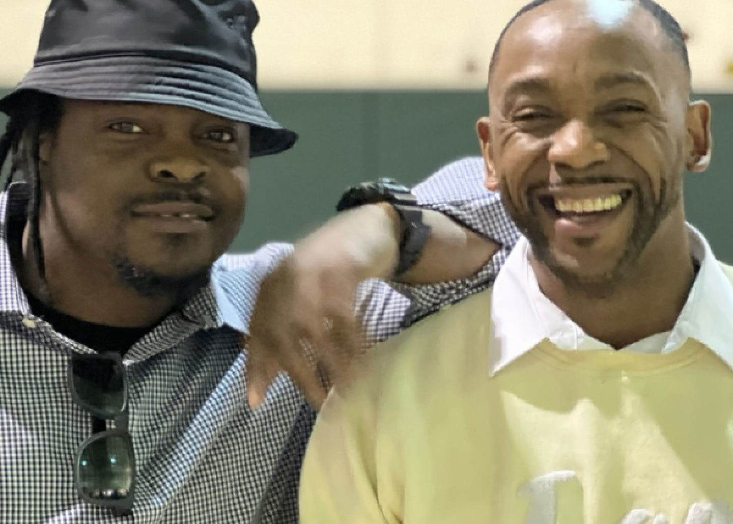 Two men, Angelo and Tamar, pose and smile at the camera.