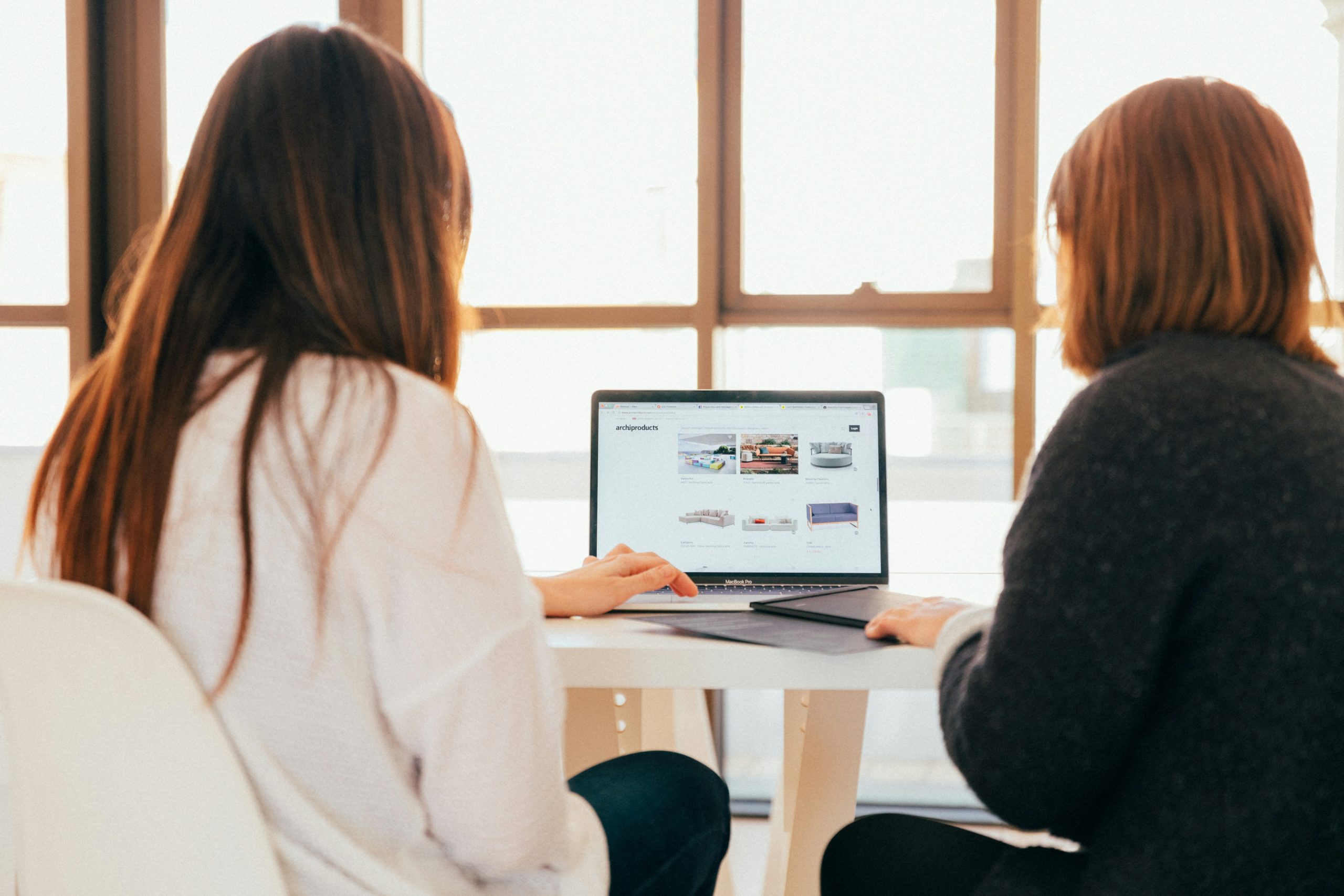 Two women look at a laptop screen.